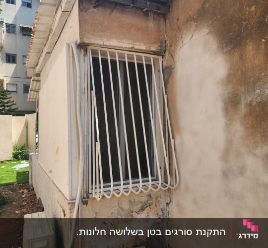 סורגי מתכת לבנים עם בטן המותקנים על חלון חיצוני